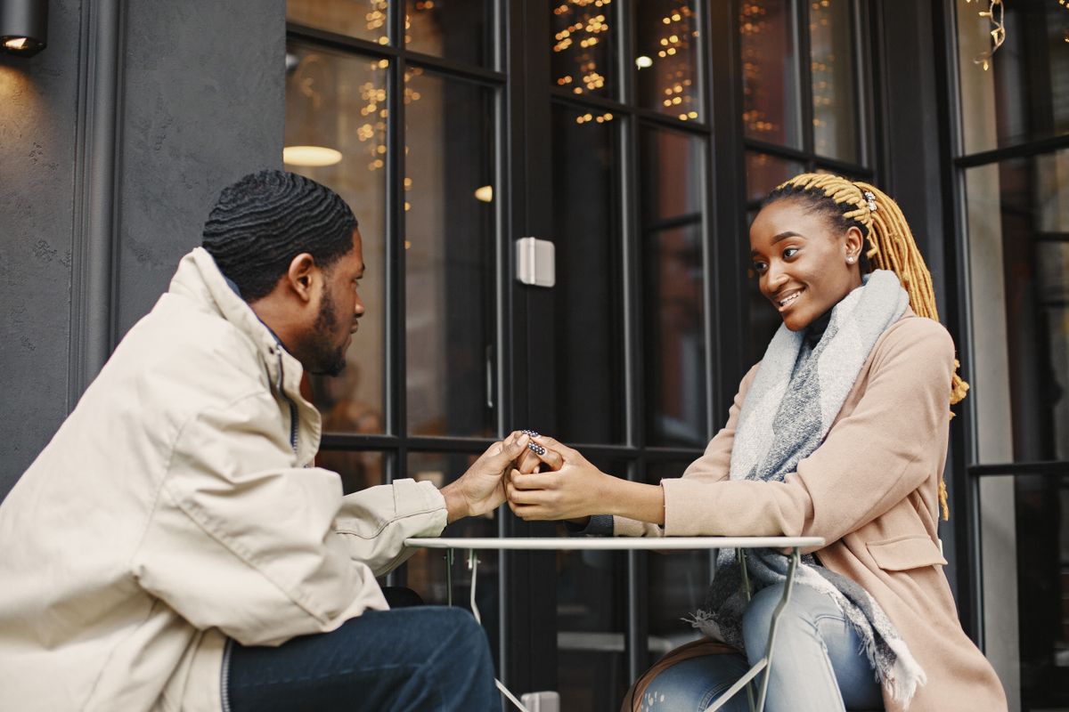 Un homme et une femme se tiennent la main à la table d’un café