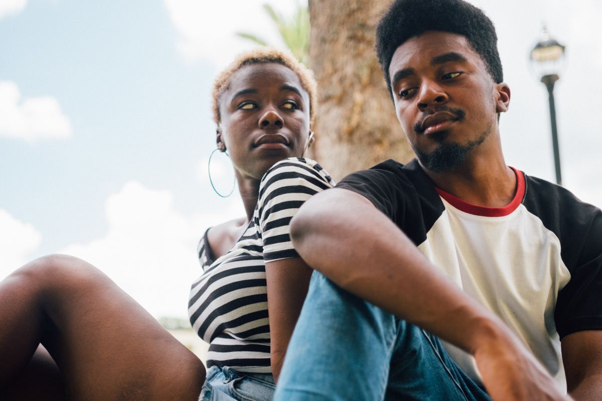 Un jeune couple assis côte à côte en plein air