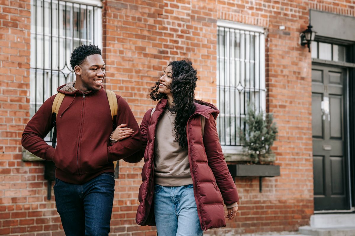 Un homme et une femme se promènent ensemble devant une façade de briques