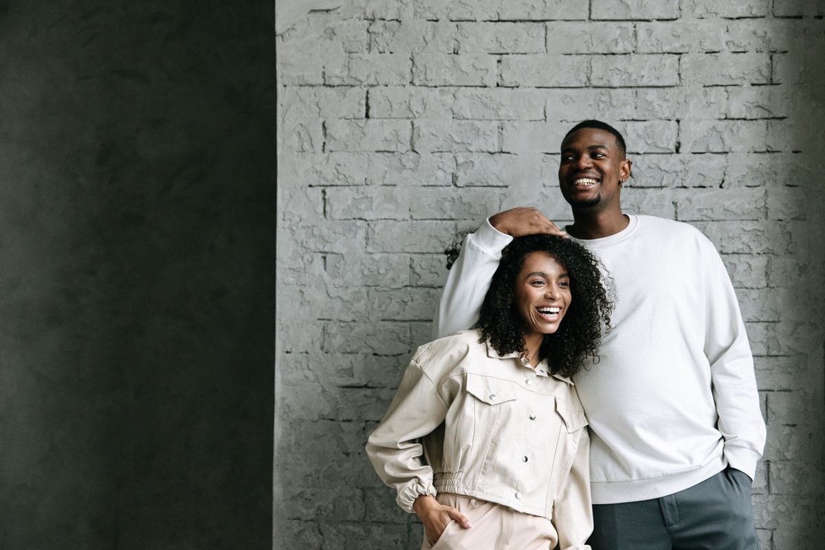Un couple souriant pose devant un mur de briques
